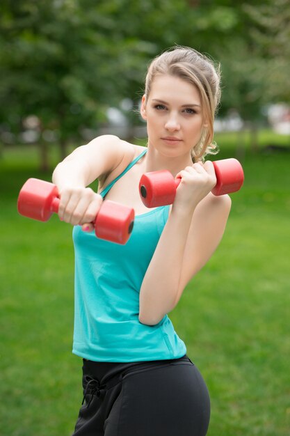 Bawi się dziewczyny ćwiczenie z dumbbells w parku