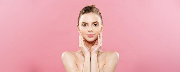 Beauty Spa Concept Kaukaska kobieta z idealną skórą twarzy Portret Piękna brunetka Spa Dziewczyna pokazująca pustą przestrzeń na białym tle na różowym tle studio Proponowanie produktu