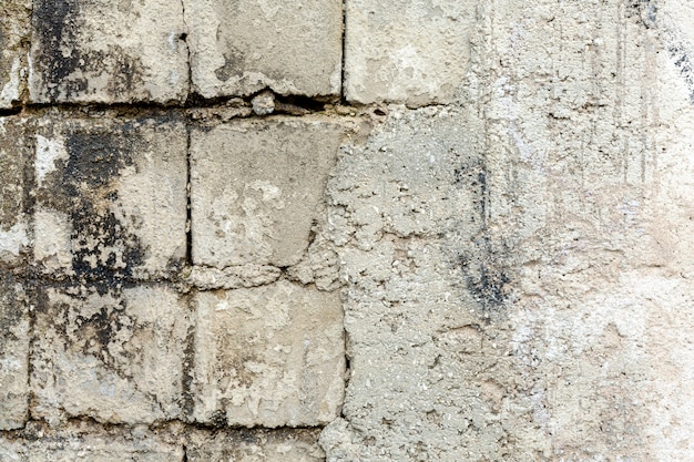 Betonowa ściana z odsłoniętymi starymi cegłami