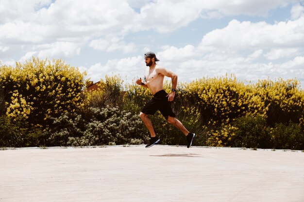 Bez koszuli męska atleta biega blisko pola