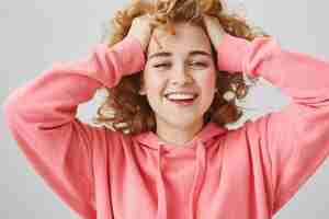 Bezpłatne zdjęcie beztroski szczęśliwa nastolatka śmiejąca się, dotykająca włosów