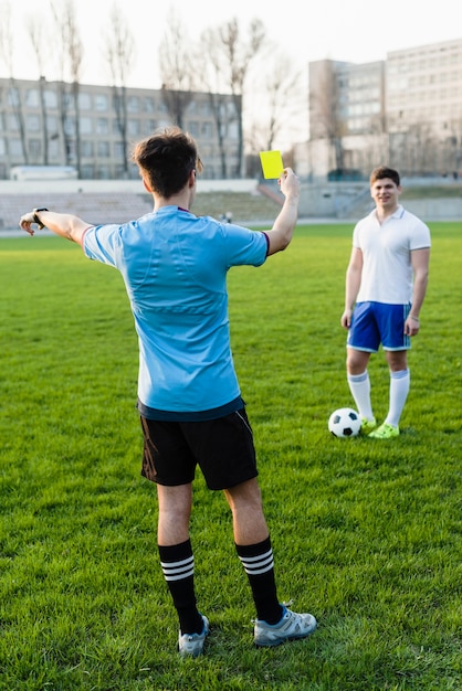 Bezpłatne zdjęcie beztwarzowy arbiter pokazuje żółtą kartkę sportowiec