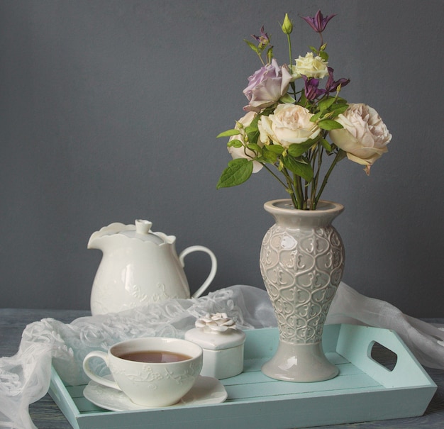 Biała filiżanka kawy, czajnik i wazon z kwiatami