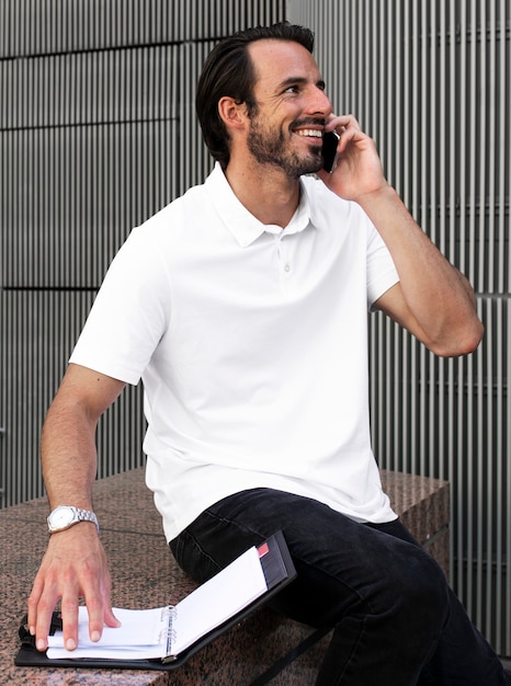 Bezpłatne zdjęcie biała koszulka polo mężczyzna rozmawia przez telefon odzież męska odzież moda