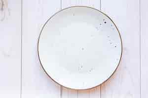 Bezpłatne zdjęcie biała płyta ceramiczna na powierzchni drewna, widok z góry