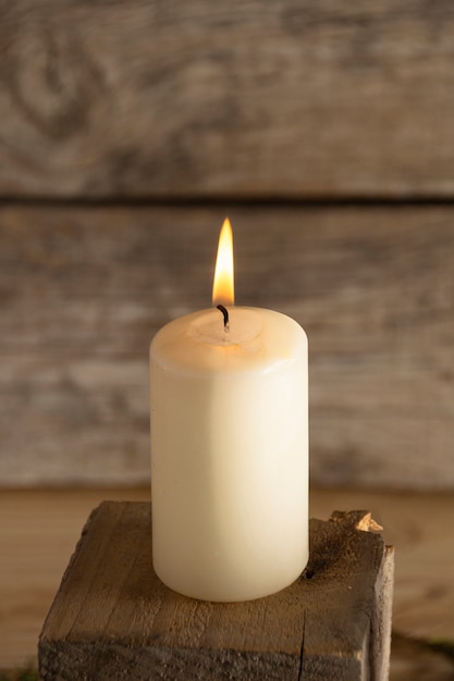 Biała zimowa świeca na drewnianym sześcianie