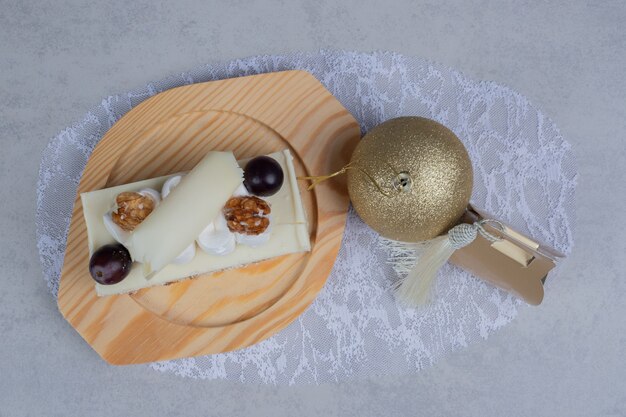 Białe ciasto czekoladowe na drewnianym talerzu z prezentem świątecznym i piłką. Wysokiej jakości zdjęcie