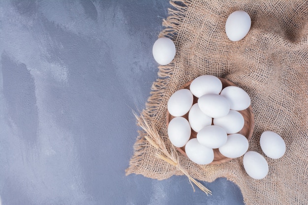Białe jajka w drewnianym talerzu na płótnie