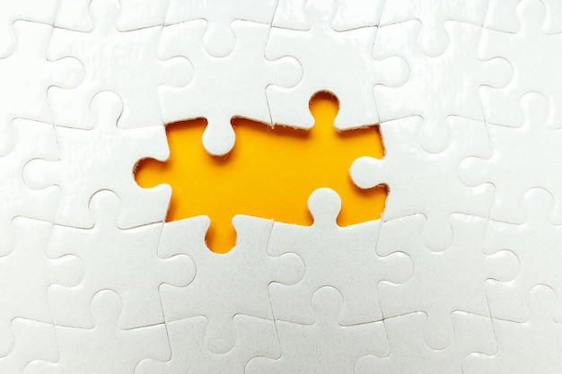 Białe puzzle bez dwóch puzzli na pomarańczowym tle