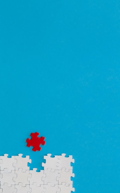 Białe puzzle i jedna czerwona na niebieskim tle leżała płasko