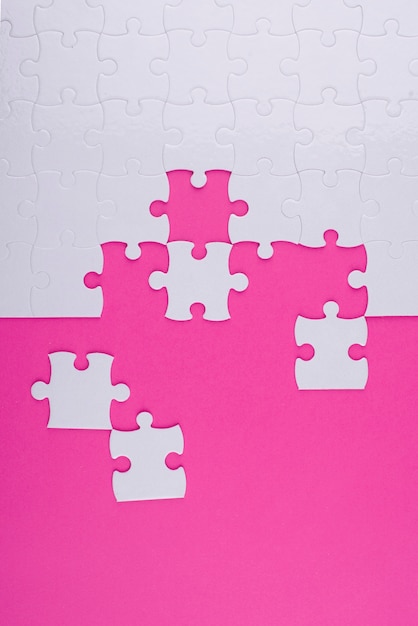 Bezpłatne zdjęcie białe puzzle i widok z góry na różowym tle