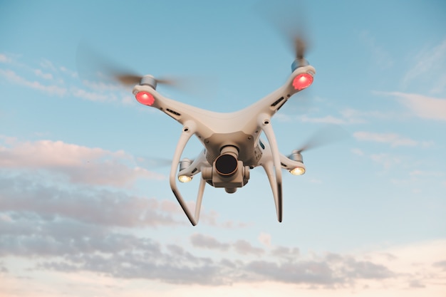 Bezpłatne zdjęcie biały dron unoszący się na jasnym błękitnym niebie