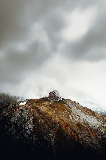 Biały i brązowy dom na szczycie brązowej góry pod białymi chmurami