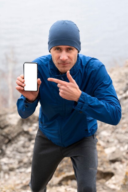 Biegacz mężczyzna pokazuje pusty telefon w przyrodzie