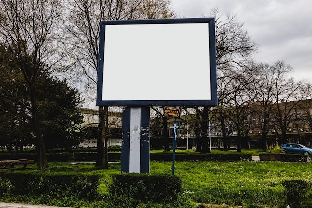 Bezpłatne zdjęcie billboardu sztandar na zielonej trawie przed budynkiem mieszkaniowym