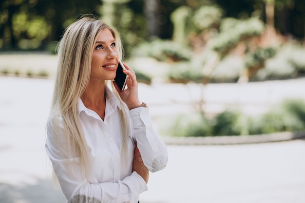 Biznes kobieta rozmawia przez telefon w parku