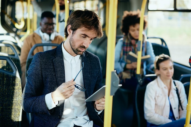 Biznesmen czytający e-mail na touchpadzie podczas dojazdów autobusem