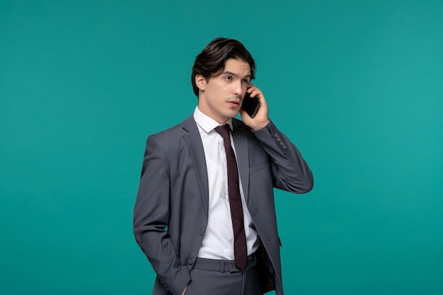 Biznesmen ładny młody przystojny mężczyzna w szarym biurowym garniturze i krawacie podczas rozmowy telefonicznej