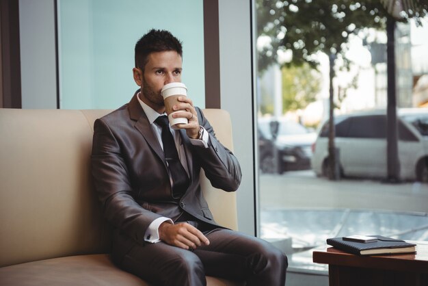 Biznesmen ma kawę podczas gdy siedzący na kanapie