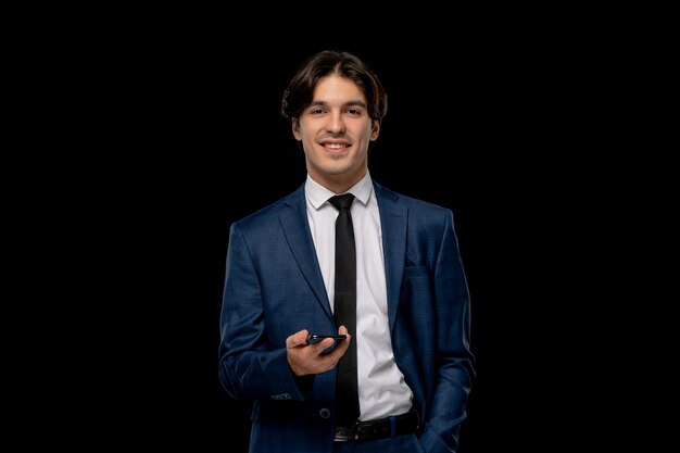 Biznesmen młody ładny mężczyzna w ciemnoniebieskim garniturze z krawatem trzymającym telefon
