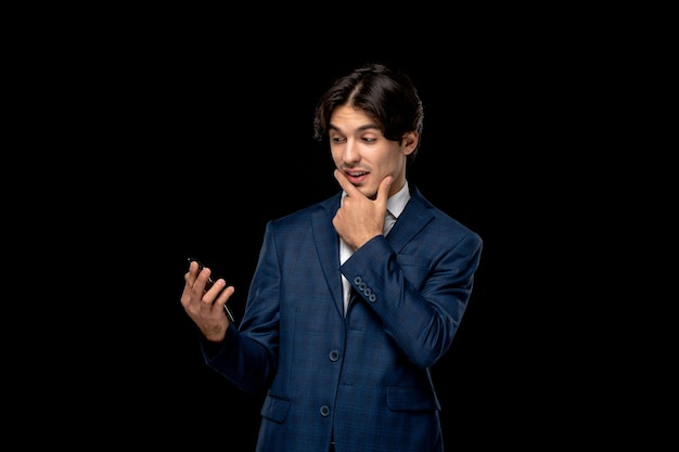 Biznesmen młody przystojny mężczyzna w ciemnoniebieskim garniturze z krawatem patrząc na ekran telefonu