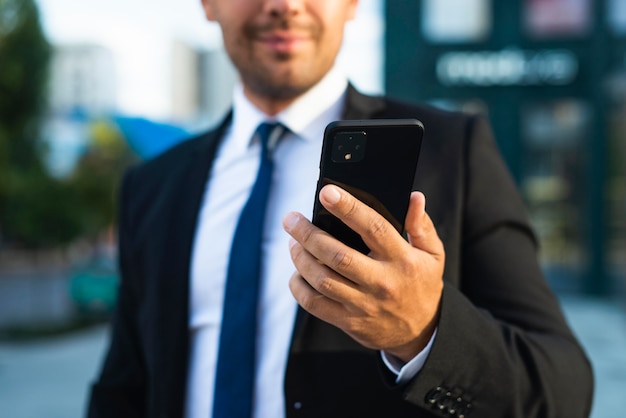 Biznesmen na zewnątrz patrząc na swój telefon