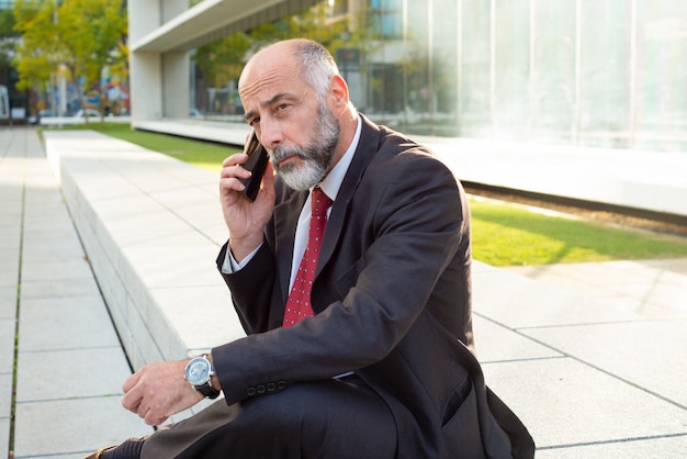 Biznesmen opowiada na smartphone i patrzeje na boku