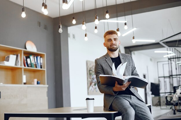 Biznesmen pracuje w biurze. Mężczyzna trzyma folder. Facet siedzi w biurze