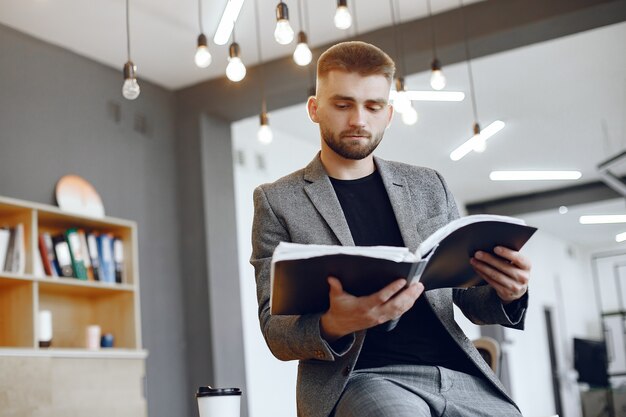 Biznesmen pracuje w biurze. Mężczyzna trzyma folder. Facet siedzi w biurze