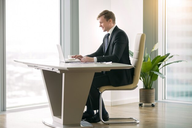 Biznesmen pracuje z laptopem przy moderm biurkiem