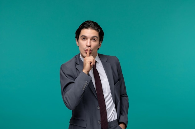 Biznesmen przystojny ładny brunetka facet w szarym garniturze biurowym i krawacie pokazując gest ciszy