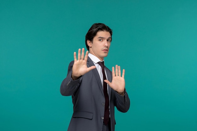 Biznesmen przystojny młody facet brunetka w szarym biurowym garniturze i krawacie pokazując znak stop