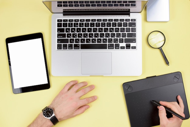 Biznesmen ręka używać graficzną cyfrową pastylkę z laptopem i cyfrową pastylką na żółtym tle