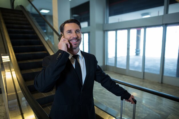 Biznesmen rozmawia przez telefon komórkowy na schodach ruchomych