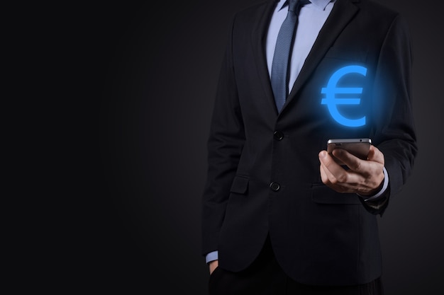 Biznesmen trzyma pieniądze monety ikony eur lub euro na ciemnym tle tonu... rosnąca koncepcja pieniędzy na inwestycje biznesowe i finanse