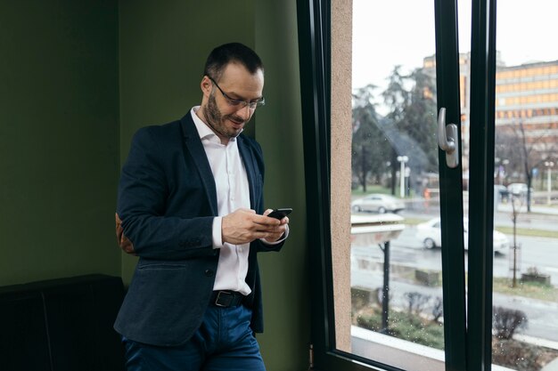 Biznesmen używa smartphone blisko okno