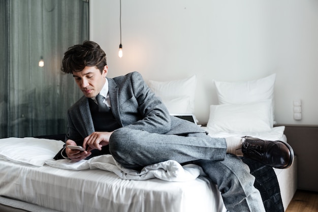 Biznesmen używa smartphone podczas gdy kłamający na łóżku