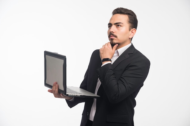 Biznesmen w dress code pozuje z laptopem.