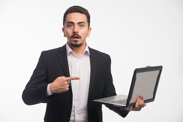 Biznesmen W Dress Code Trzymając Laptopa I Wskazując Na Niego.