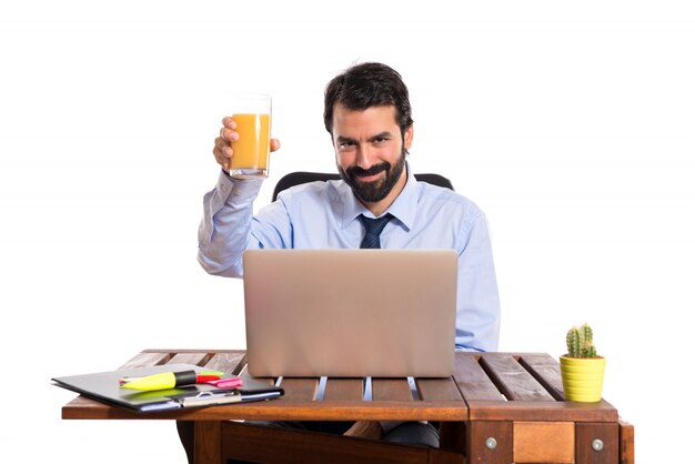 Biznesmen w swoim biurze pije sok pomarańczowy