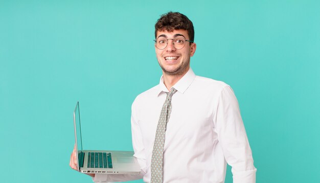 Biznesmen z laptopem wyglądający na szczęśliwego i mile zaskoczonego, podekscytowany z wyrazem fascynacji i szoku