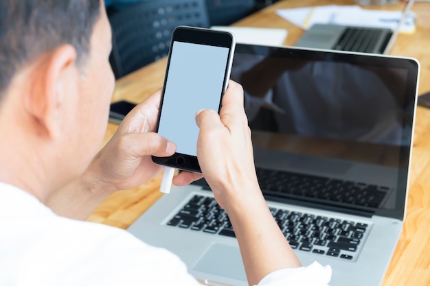 Biznesmen za pomocą telefonu komórkowego i laptopa.