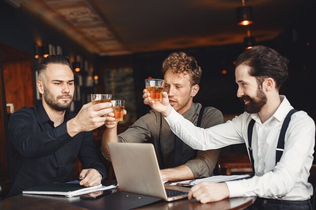 Biznesmeni w negocjacjach. Mężczyźni z alkoholem siedzący przy stole. Przyjaciele rozmawiają.