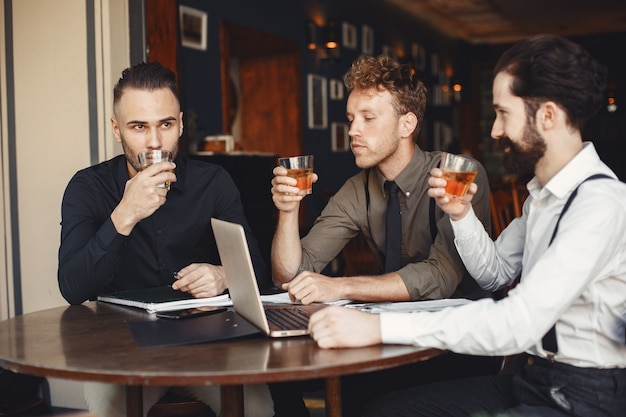 Biznesmeni w negocjacjach. Mężczyźni z alkoholem siedzący przy stole. Przyjaciele rozmawiają.