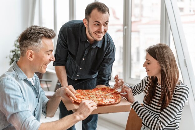 Biznesmeni w przerwie obiadowej jedzą pizzę