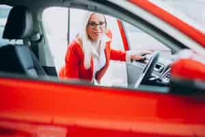 Bezpłatne zdjęcie biznesowa kobieta patrzeje dla samochodowej wiszącej ozdoby przy samochodową sala wystawową
