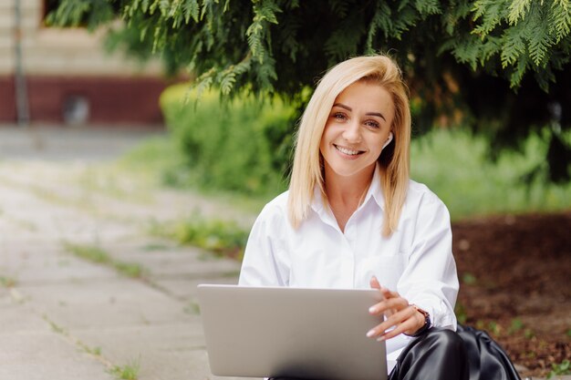 Biznesowa kobieta pracuje na laptopie outside w miasto parku