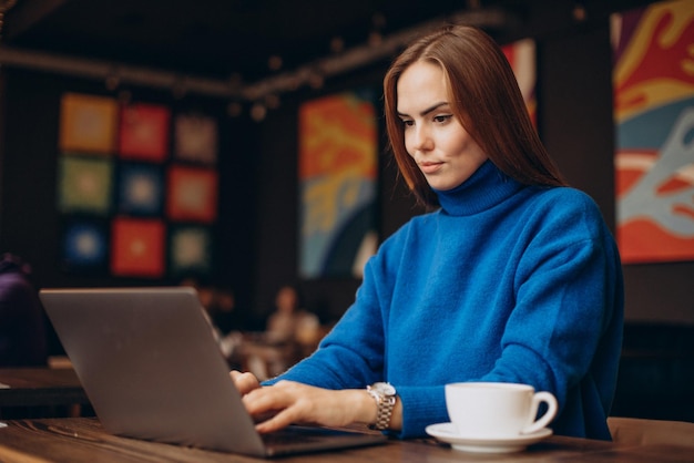 Biznesowa kobieta pracuje na laptopie w kawiarni