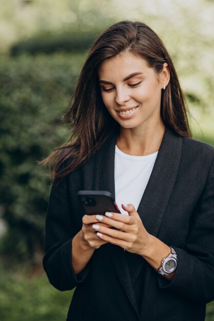 Biznesowa kobieta rozmawia przez telefon w parku