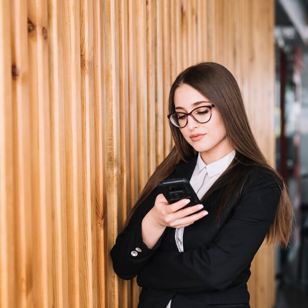 Biznesowa kobieta używa smartphone przy ścianą